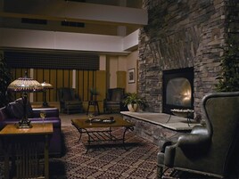 Una sala de estar con chimenea de piedra, muebles de cuero y televisión.