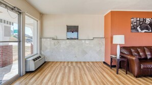 A hotel room with a wooden floor, a reception desk, a brown leather sofa, and a wall-mounted picture. - Hotel Waco University Area/ I-35 (Waco)