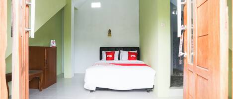A bedroom with a bed, a wooden cabinet, and a door.