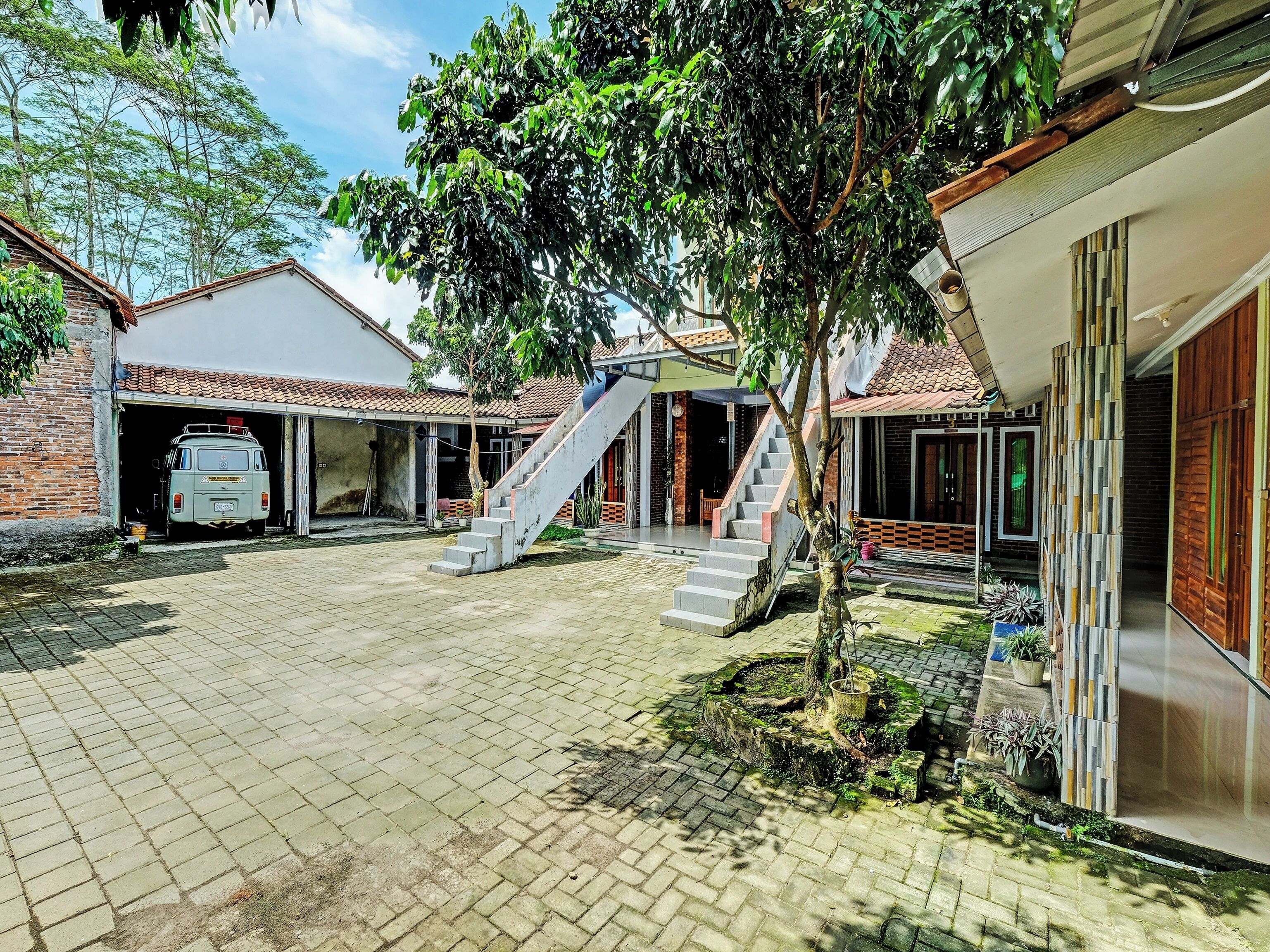 A courtyard with a van, a staircase, and a tree.