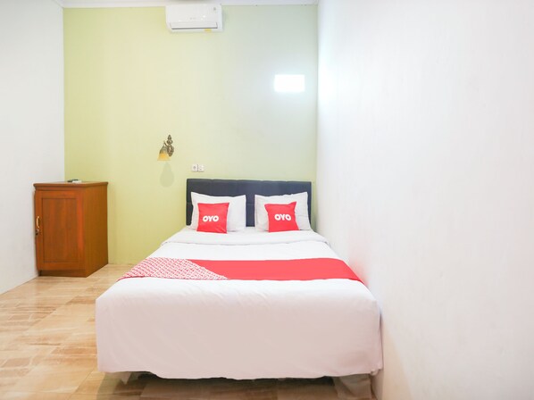 Ein Schlafzimmer mit einem Bett, einem Holzschrank und einer Wand-Klimaanlage.