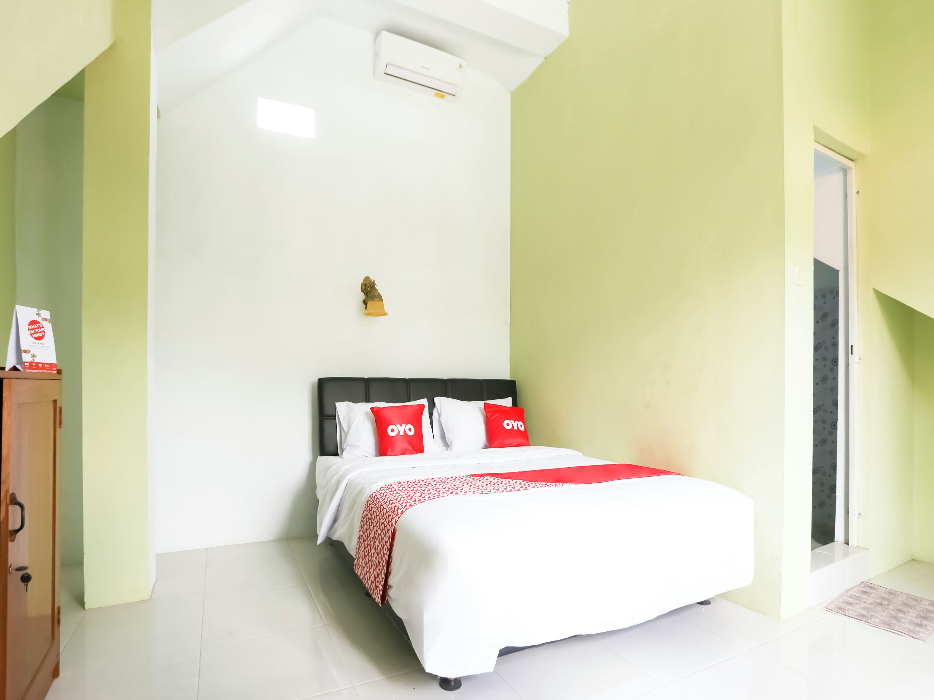 A neatly arranged bedroom with a bed, a small statue, and a door leading to another room.