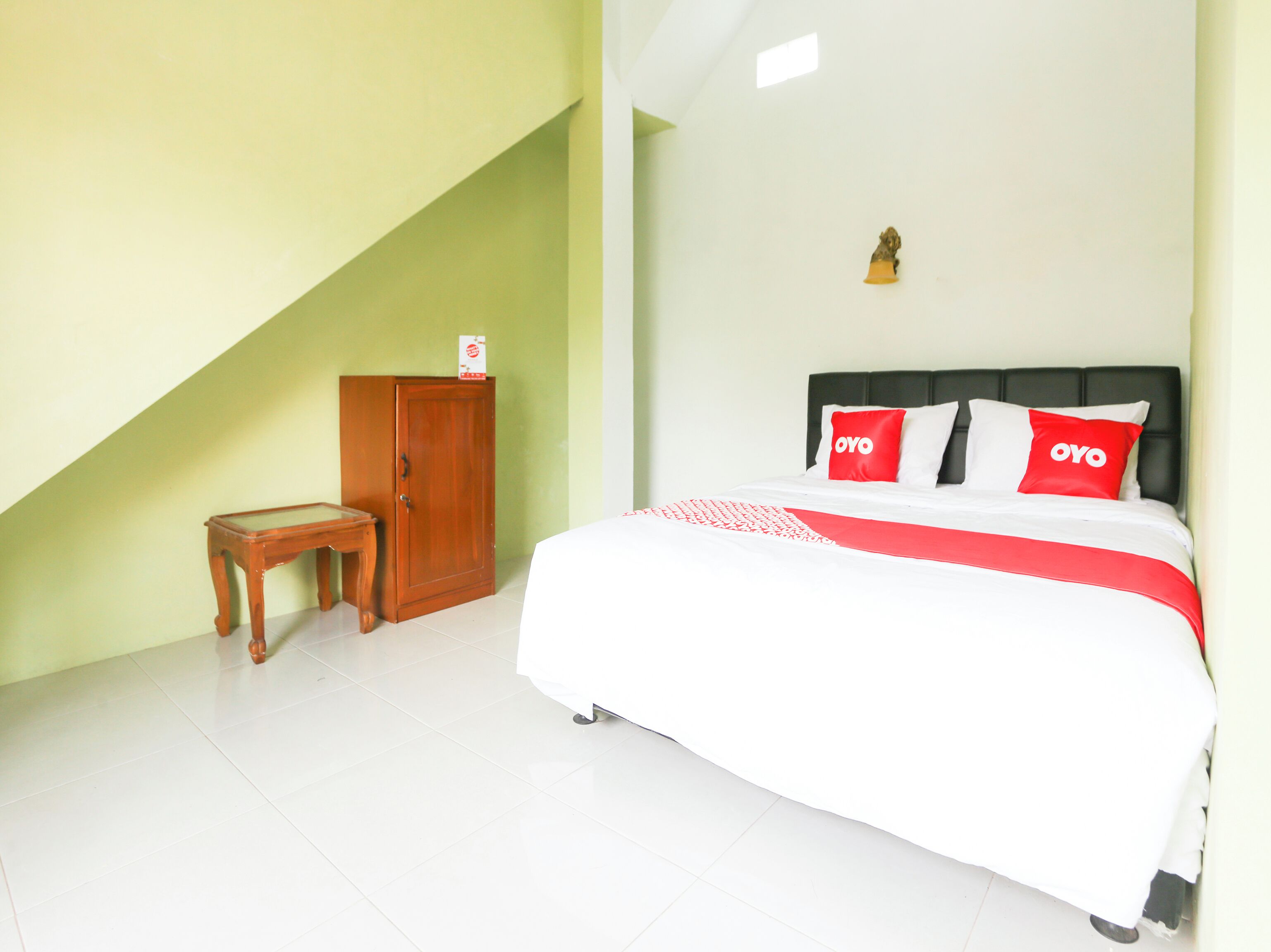 A bedroom with a bed, a nightstand, a wooden cabinet, and a small table.