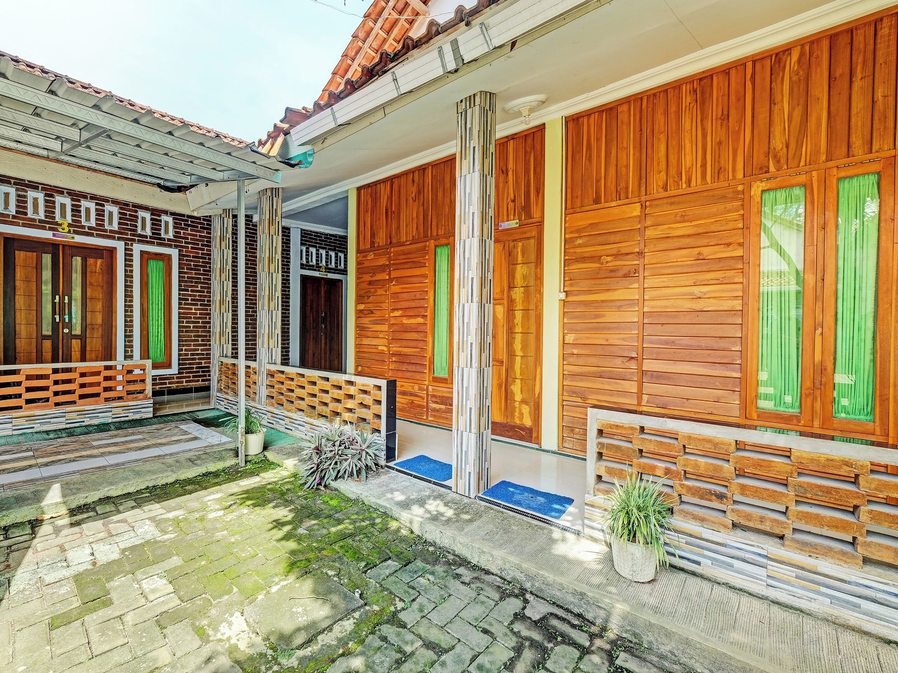 Une maison traditionnelle en bois, avec un toit en tuiles, un porche en bois et un petit jardin.