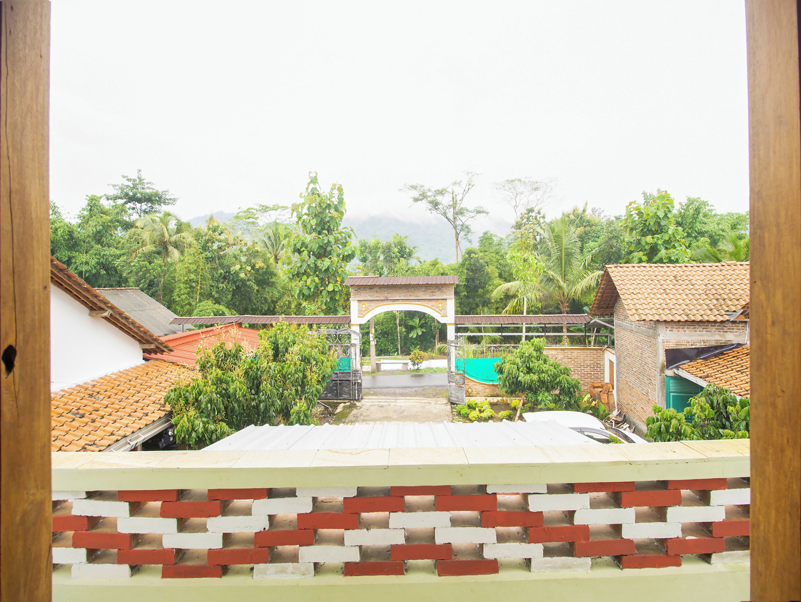 A courtyard with a brick wall, a tiled roof, and a central archway.