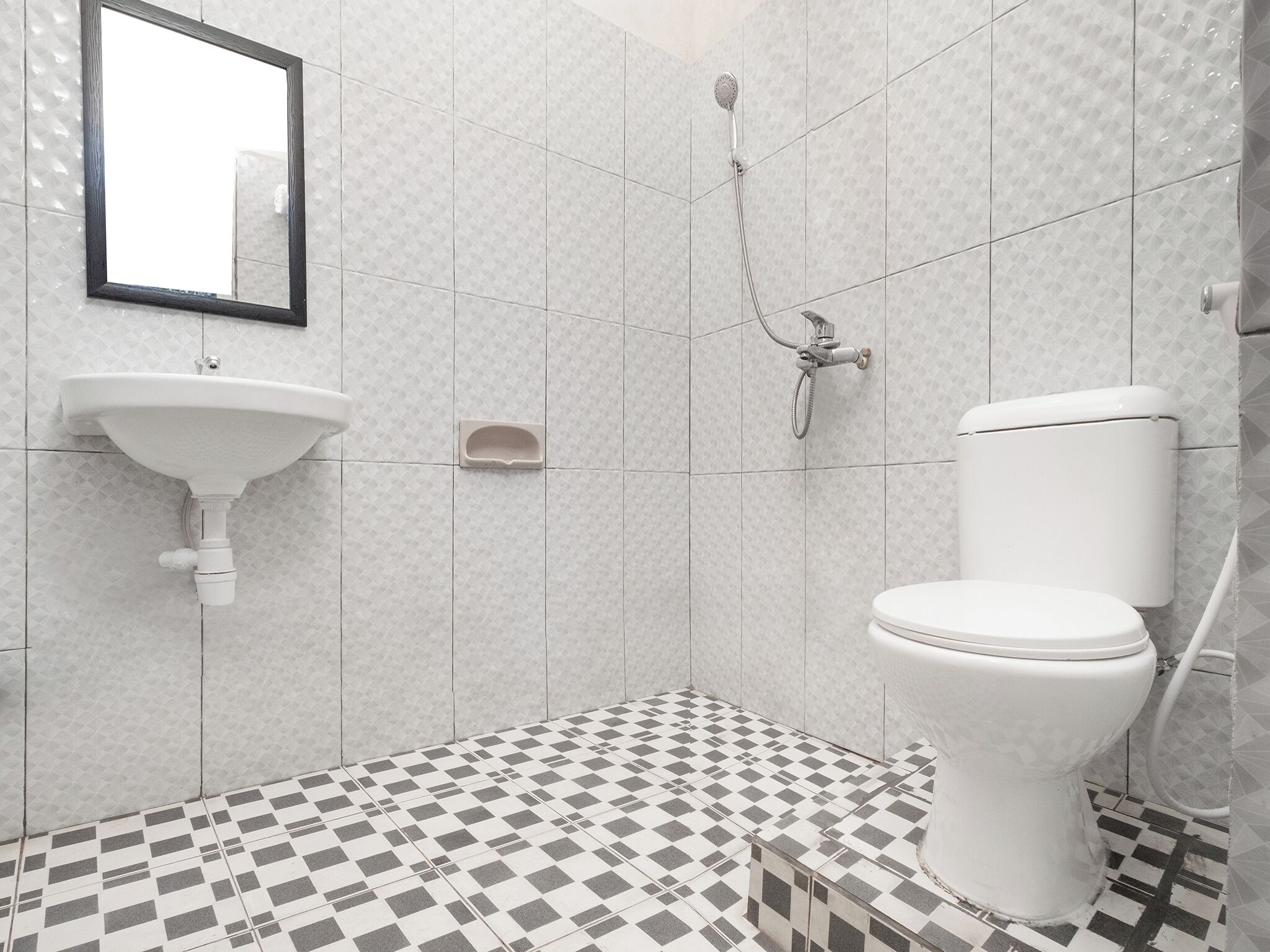 A bathroom with a white sink, toilet, and shower. The floor has a checkered tile pattern.