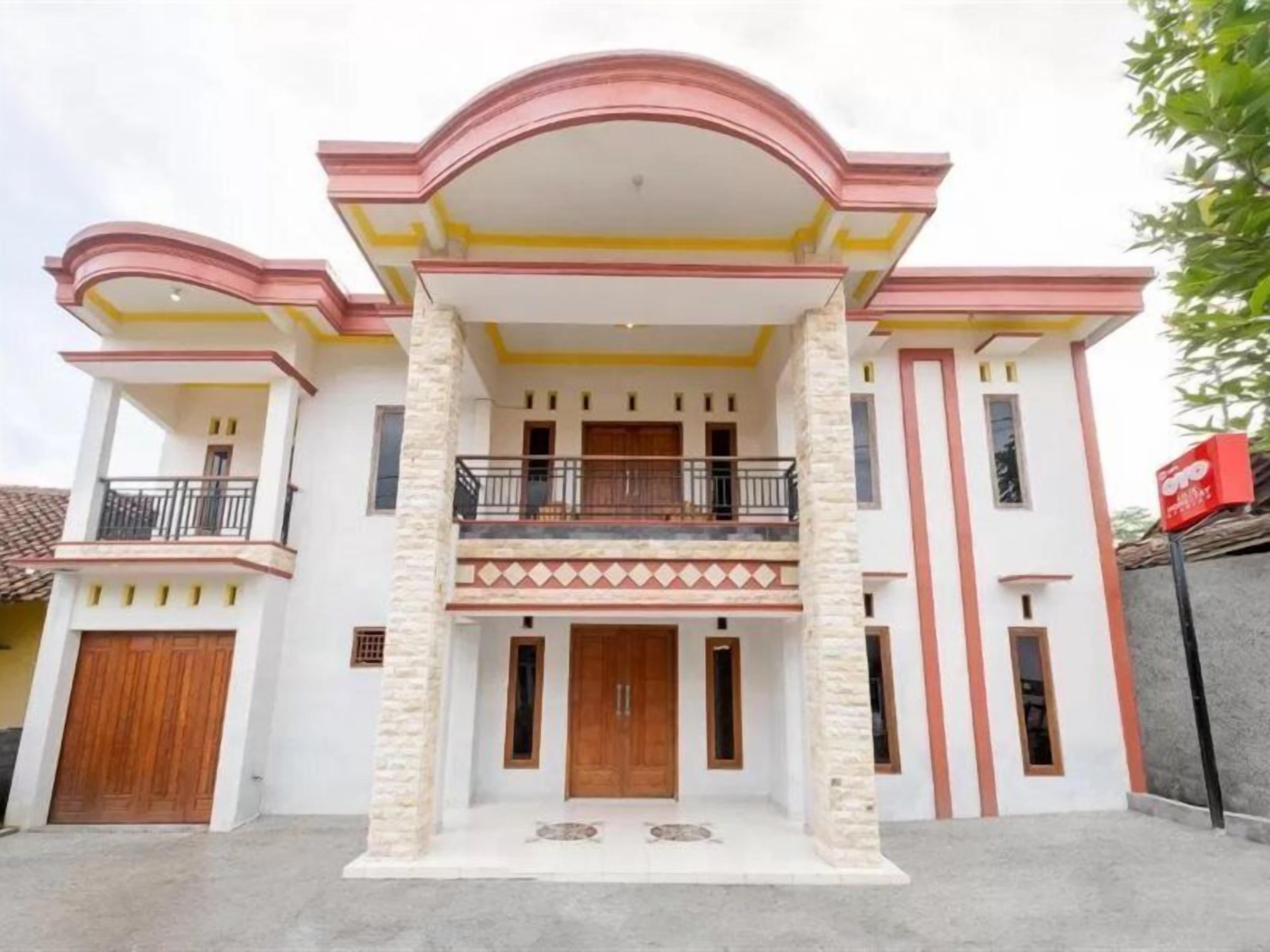 A two-story building with a central entrance, balconies, and a red mailbox.