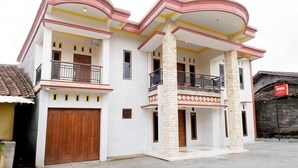 A two-story house with a balcony, a garage, and a stone pillar.