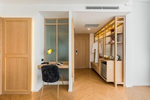 Une pièce de taille modeste, comprenant un bureau en bois, une chaise noire, une armoire et une étagère où sont rangés divers objets.