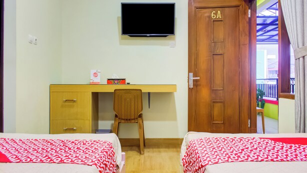 A hotel room with two beds, a desk, a chair, a television, and a door marked with the number 6A. - OYO 3418 Penginapan May Lindon Syariah (Cipanas)