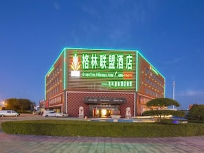 A hotel with a prominent green neon sign, multiple floors, and a well-maintained exterior. - Greentree Alliance Tianjin Jinnan Balitai Taihe Building Hotel (Tianjin)