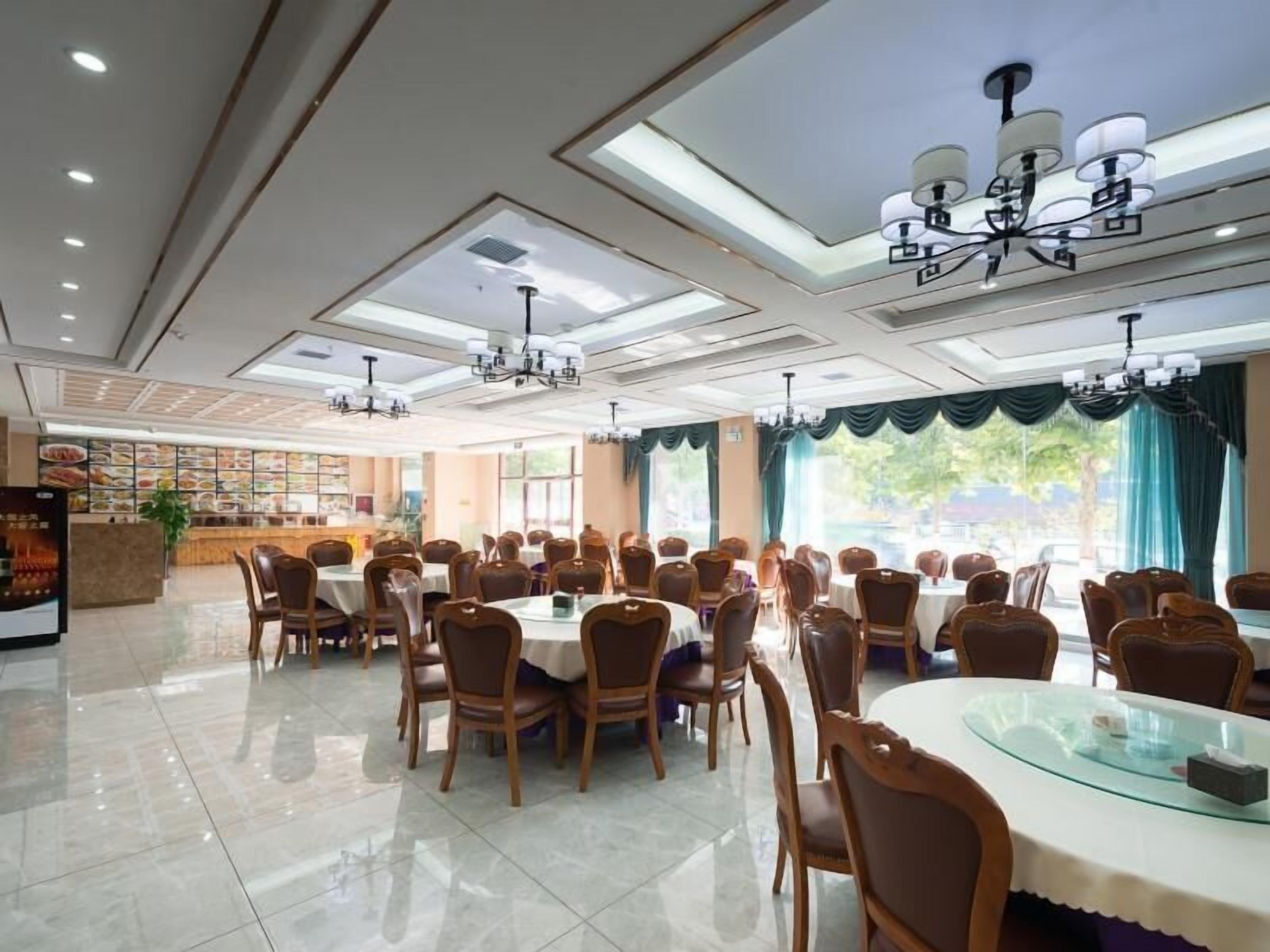 A spacious dining area with multiple tables and chairs, a reception desk, and a menu display.