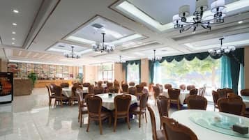 A spacious dining area with multiple tables and chairs, a reception desk, and a menu display.