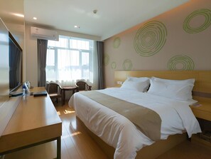 Ein Hotelzimmer mit Bett, Schreibtisch, Stuhl und Fernseher.