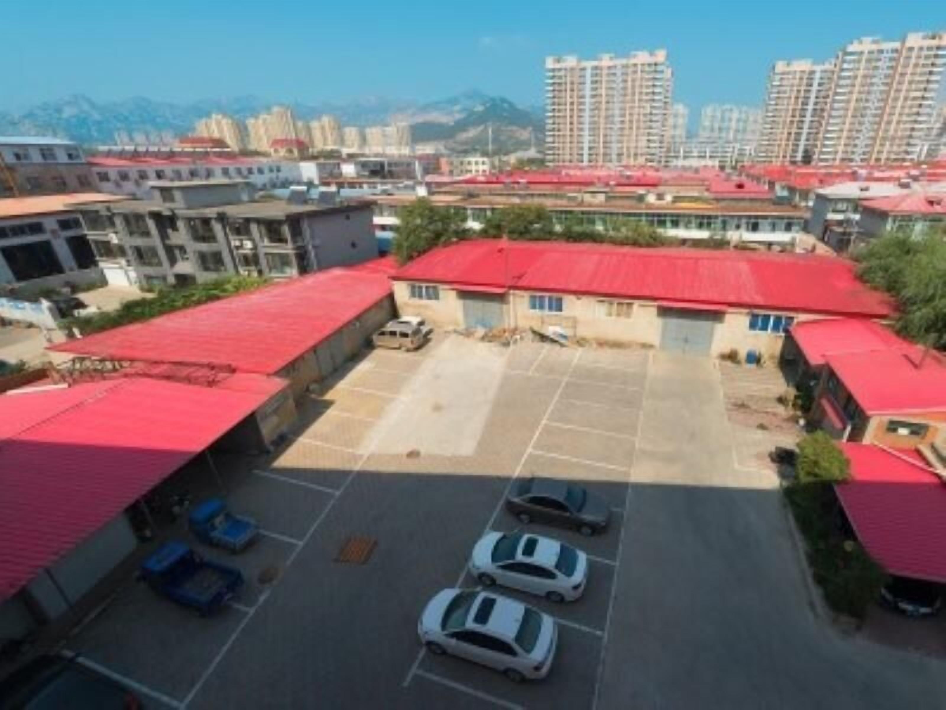A parking lot with several cars, surrounded by buildings with red roofs.