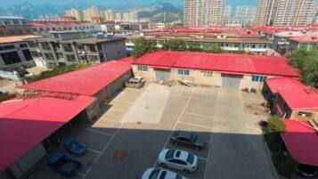 A parking lot with several cars, surrounded by buildings with red roofs.