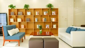 A modern living room with a large bookshelf, two sofas, a coffee table, and a TV. - Greentree Inn Shangqiu Suiyang Avenue Hotel (Shangqiu)