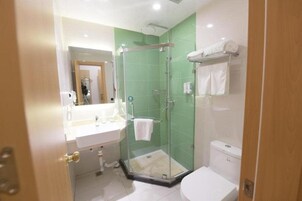 Un baño con cabina de ducha de vidrio, un lavabo blanco y un inodoro.
