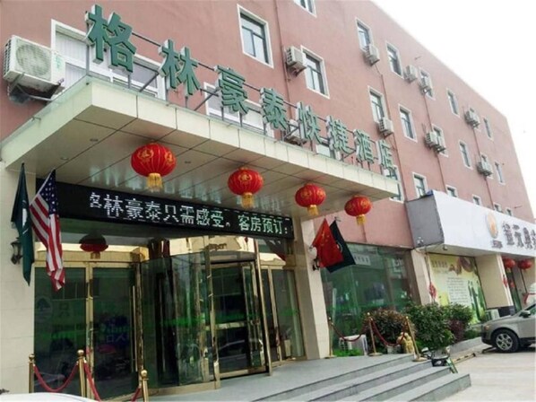 A hotel entrance with a glass door, red lanterns, and an American flag. - Greentree Inn Anhui Bozhou Mengcheng Zhuangzi Road Express Hotel (Bozhou)