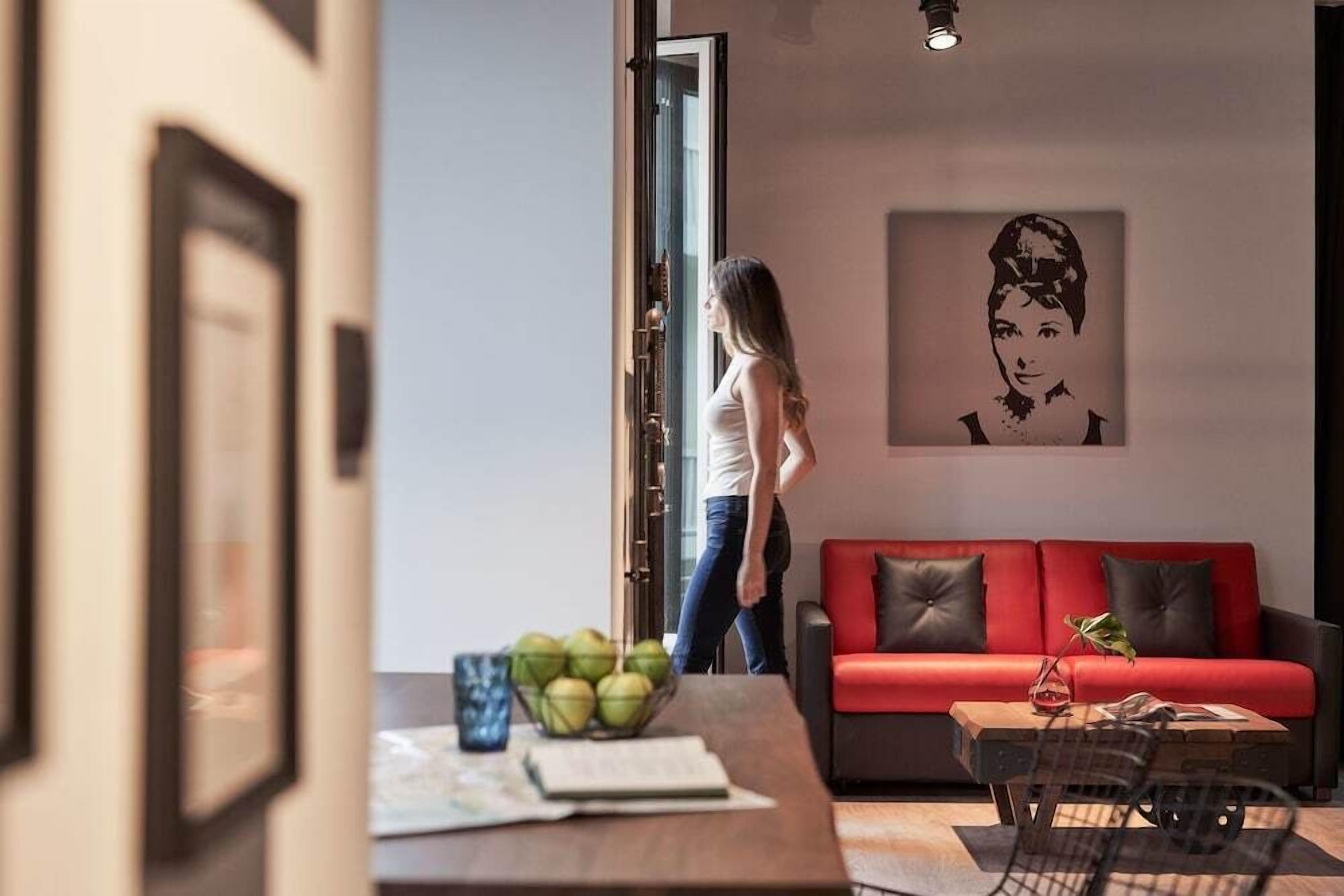 Una sala de estar moderna con un sofá rojo, una mesa de centro con un frutero y un cuadro en la pared.