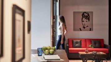 Una sala de estar moderna con un sofá rojo, una mesa de centro con un frutero y un cuadro en la pared.