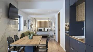Una habitación de hotel moderna con una mesa de comedor de madera, sillas negras, un sofá, una cama y una cocina integrada.