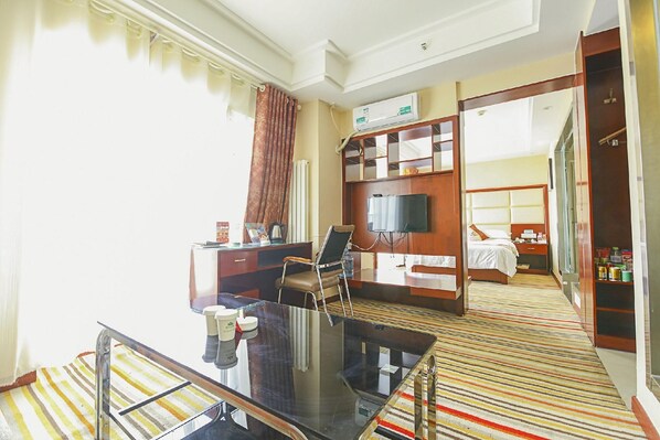 Una habitación de hotel con cama, escritorio, televisor y minibar.