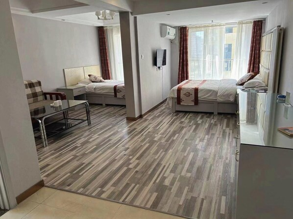 Ein modernes Hotelzimmer mit zwei Betten, einem Esstisch und einem Fernseher.
