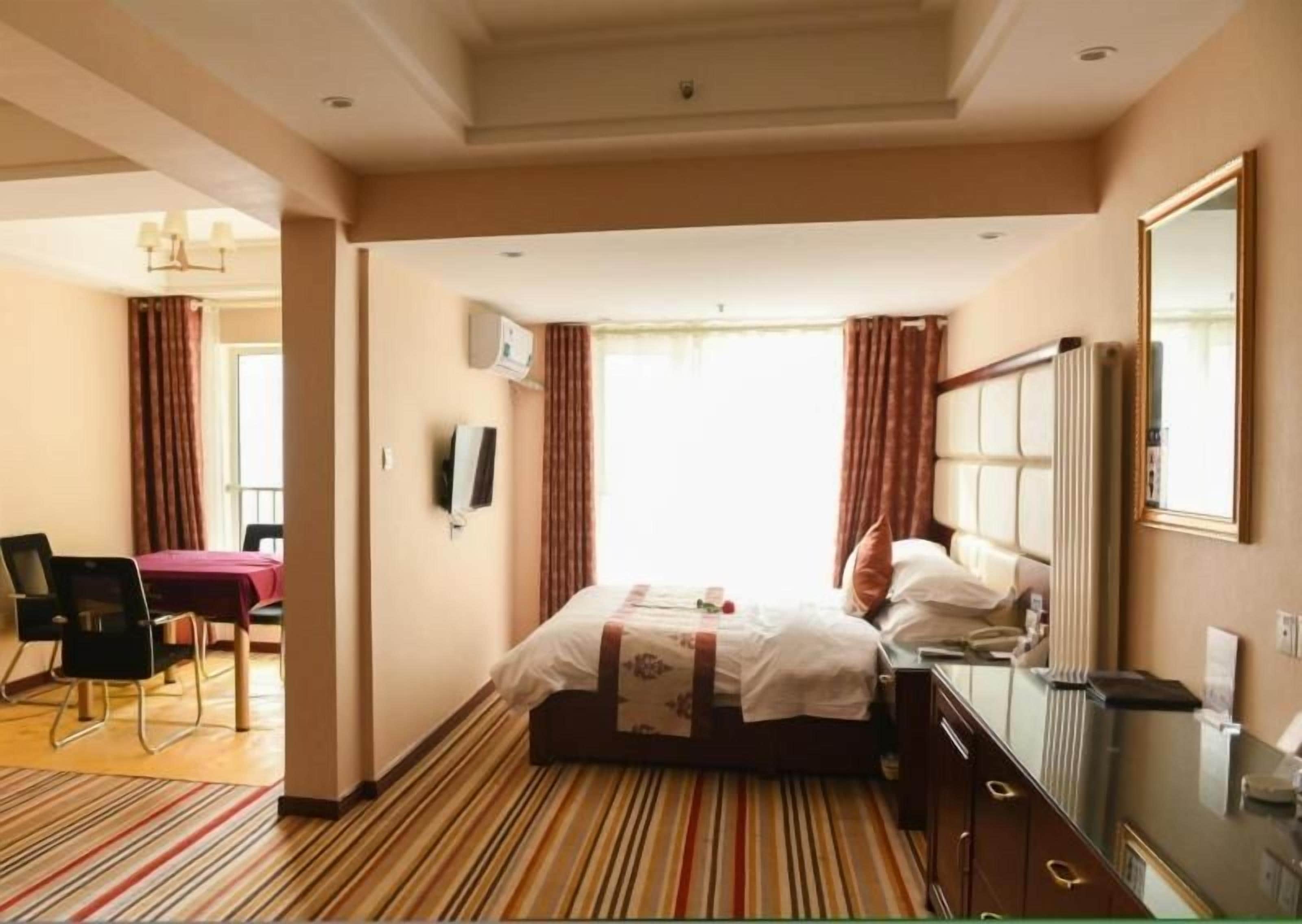 A hotel room with a bed, a desk, a chair, a television, and a window with curtains.