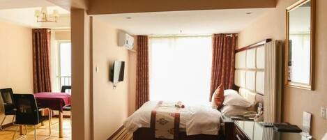 A hotel room with a bed, a desk, a chair, a TV, and a window with curtains.