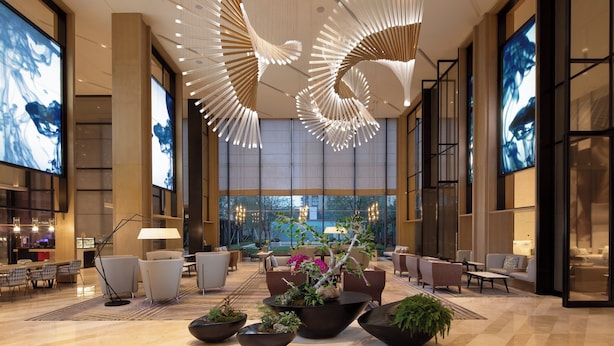 Un vestíbulo amplio con muebles modernos, una lámpara de araña grande y vistas al exterior.