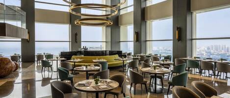 A spacious dining area with high ceilings, large windows, and a city view.