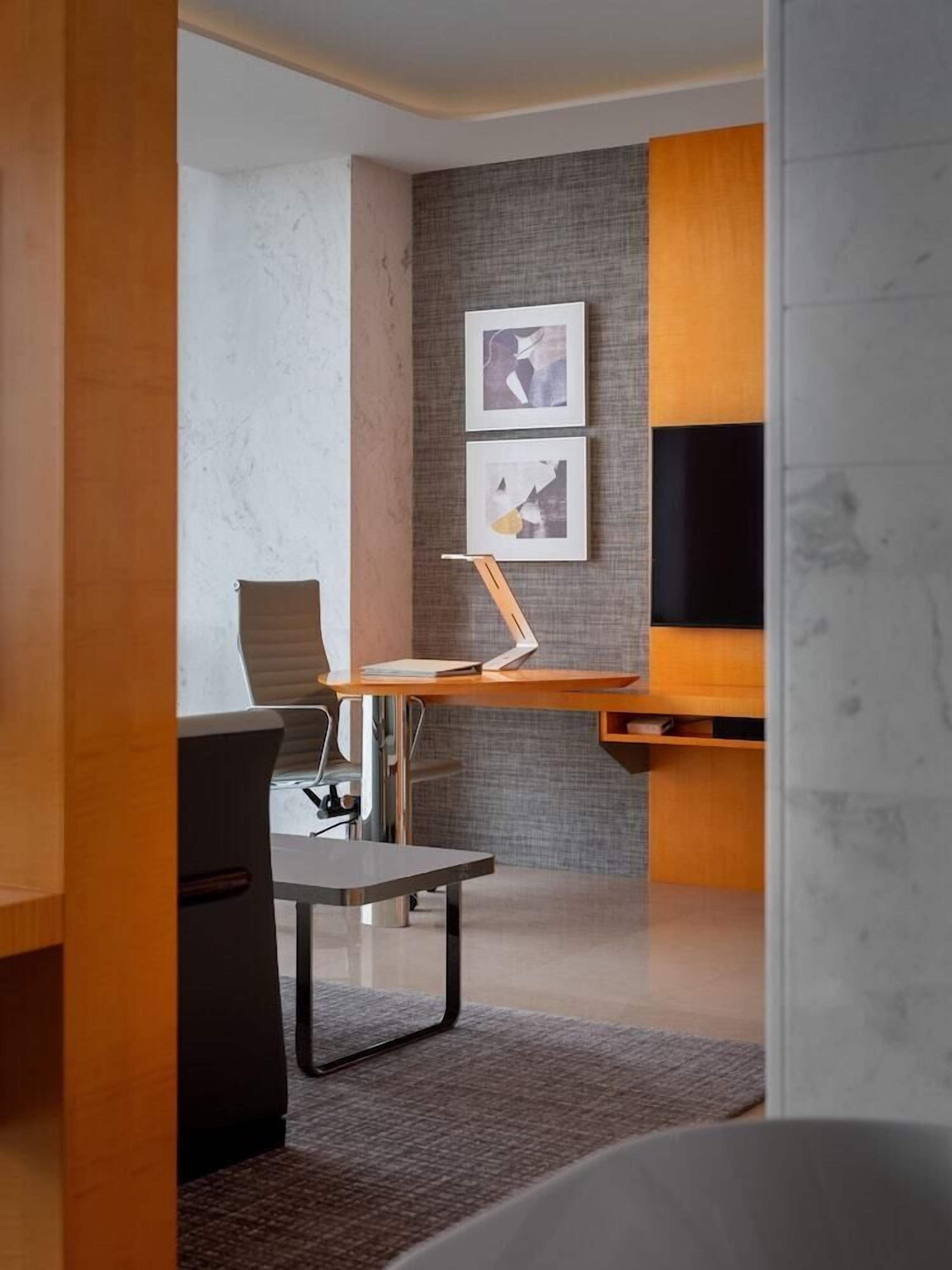 A modern office space with a desk, chair, and two framed artworks on the wall.