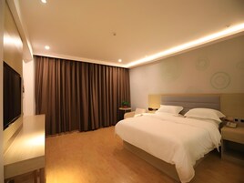 Quarto de hotel moderno com uma cama grande, televisão, mesa de cabeceira e parede com padrões circulares.