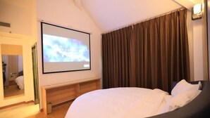 A hotel room with a bed, a large screen, a mirror, and a window with curtains. - Greentree Wudi Bus Terminal Feilong Street Store (Binzhou)