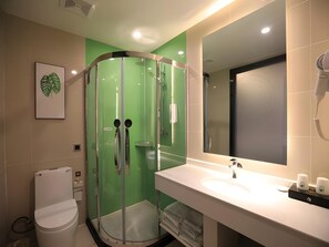 A modern bathroom with a glass-enclosed shower, a white sink with a mirror, and a toilet. - Greentree Wudi Bus Terminal Feilong Street Store (Binzhou)