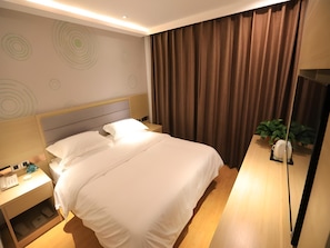 A hotel room with a bed, bedside tables, a nightstand, a mirror, a plant, and a curtain. - Greentree Wudi Bus Terminal Feilong Street Store (Binzhou)