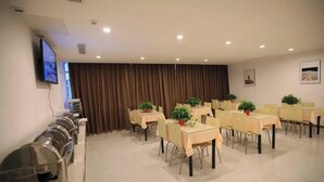 A conference room with tables, chairs, a TV, and a curtain.