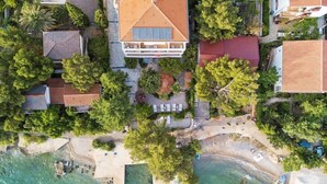 Vue aérienne d’une propriété située sur la côte, avec une grande maison, une plage et une végétation luxuriante.