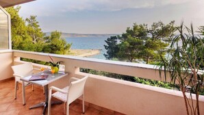 Un balcon avec une table et des chaises, donnant sur une plage et la mer.