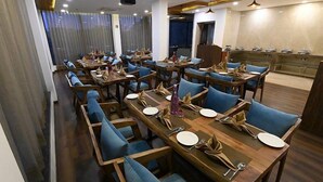 Ein Restaurant mit mehreren Tischen und blauen, gepolsterten Stühlen, ansprechend und großzügig angeordnet.