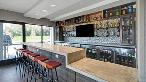 Eine moderne Bar mit einer langen Theke, mehreren Barhocker und einer Auswahl an Spirituosenflaschen.