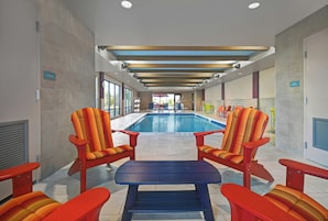 A pool area with chairs and a table, a storage sign, and a view of the pool.