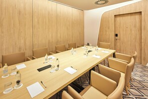Une salle de conférence avec une longue table, des chaises, des bouteilles d’eau, des verres et des porte-noms.