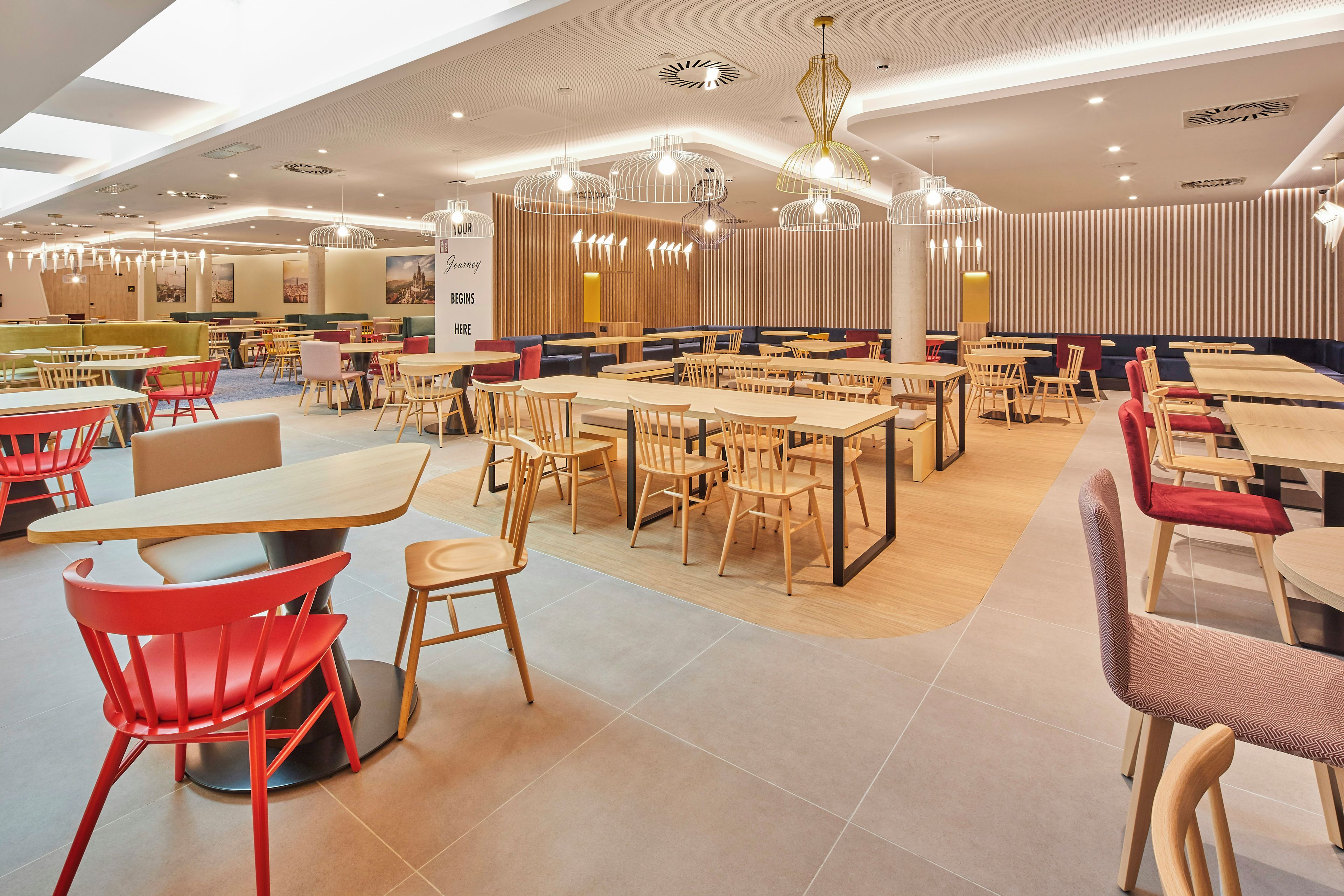 Un restaurante espacioso con varias zonas de estar, incluyendo cabinas y mesas, y una variedad de lámparas.