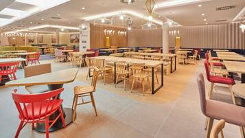 A spacious restaurant with multiple seating areas, including booths and tables, and a variety of lighting fixtures.