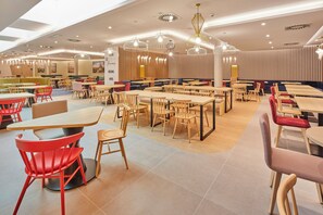 Un restaurant spacieux doté de plusieurs espaces de restauration, notamment des banquettes et des tables, ainsi que de différents types d’appareils d’éclairage.