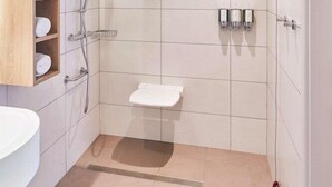 A modern bathroom with a shower, toilet, and a wooden shelf with towels. - Hampton By Hilton Barcelona Fira Gran Via (L'Hospitalet de Llobregat)