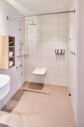 Un baño moderno con ducha, inodoro y repisa de madera con toallas.
