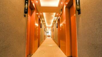 A long, well-lit hallway with doors on both sides, leading to rooms.